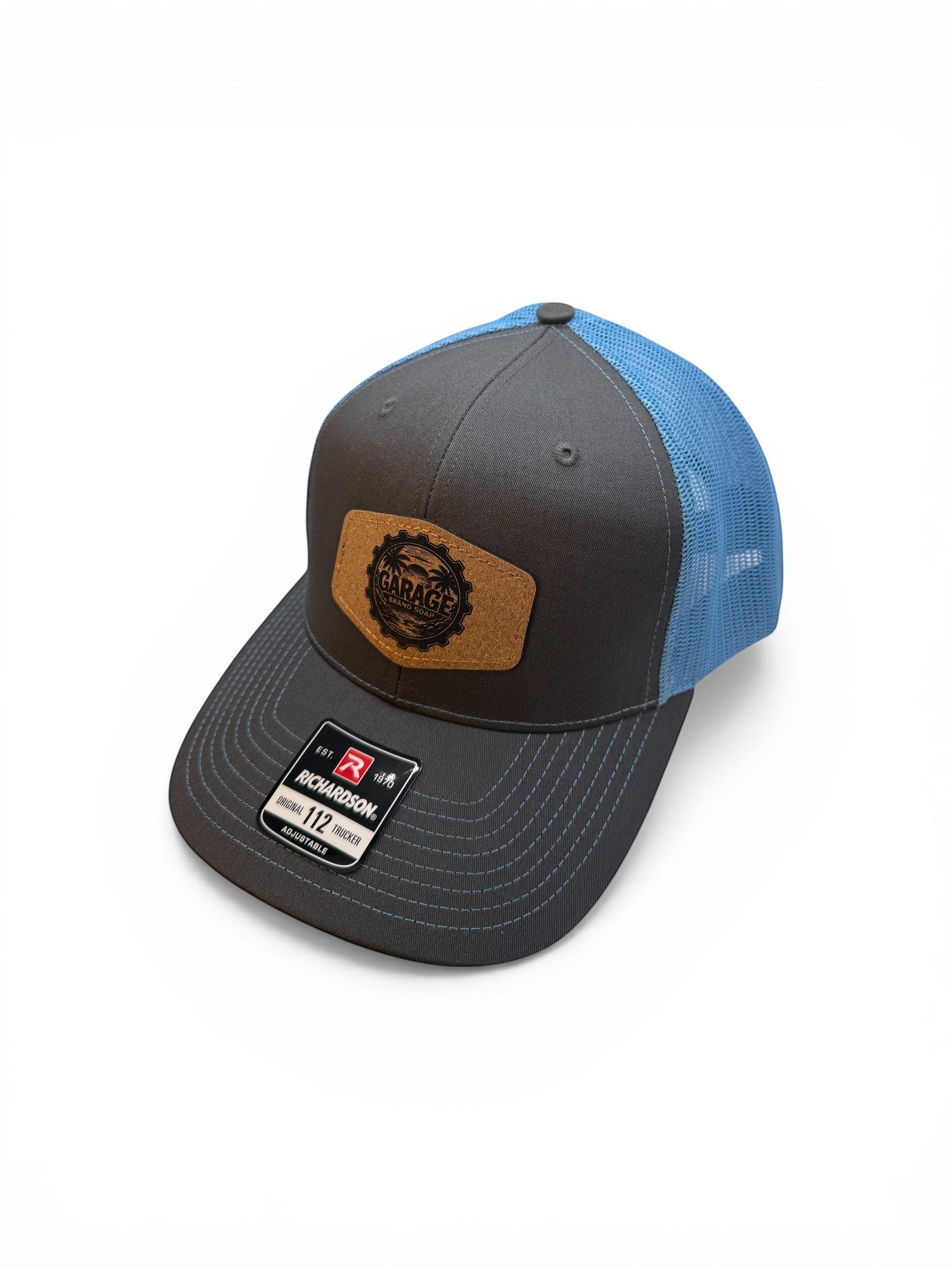 Garage Brand Soap Richardson trucker hat in charcoal grey and bright blue with a leather patch logo on the front